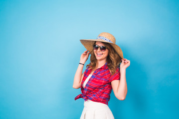Obraz na płótnie Canvas Holidays, summer, fashion and people concept - Girl in fashionable clothes straw hat. Portrait of charming woman on blue background with empty copy space