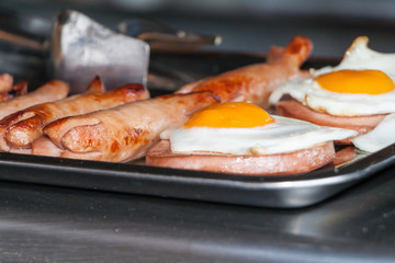 fried eggs and fried sausages on a counter in street cafe