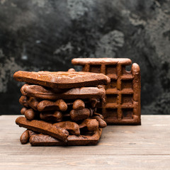 selective focus on homemade fresh rye waffles on wooden table, dark background, close-up