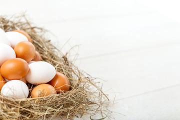 Fresh country eggs with straw on rustic wooden table, free space