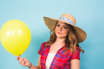 Fashion smiling young woman with yellow air balloon over colorful blue background with copyspace.