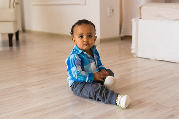 Naklejka premium Small child tries to put on his shoes. Mixed race baby boy with shoes