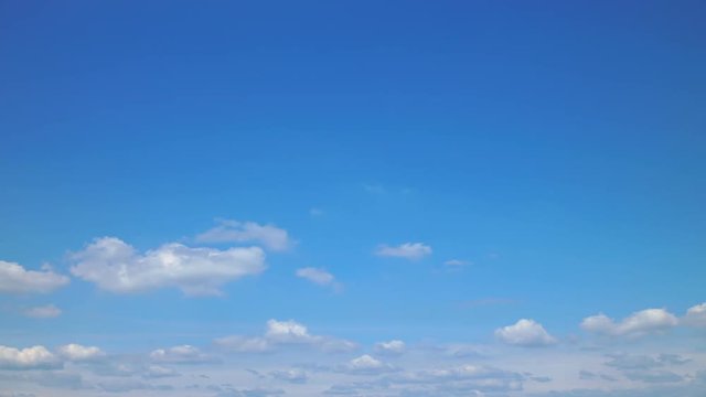 Time lapse video of white cumulus clouds morphing on the blue sky on the lower part of video, blue sky on upper part
