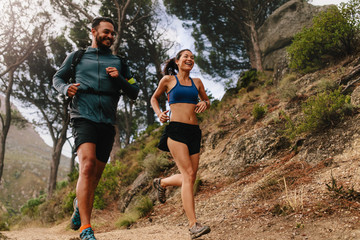 Healthy young couple running on mountain trail