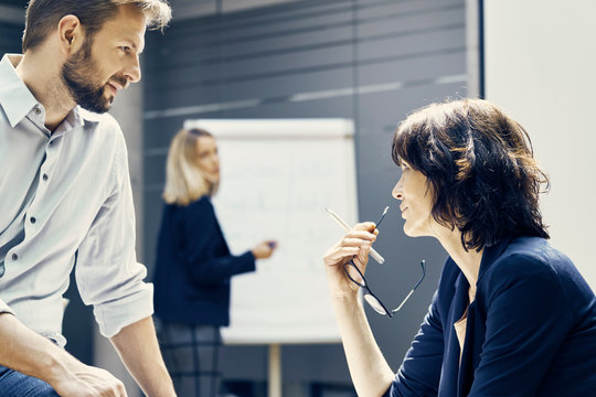 Businesswoman and man having discussion during office presentation