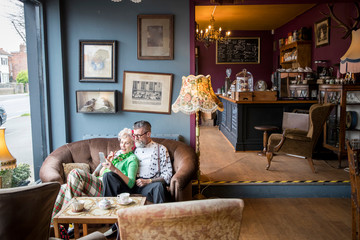 Quirky vintage couple looking at smartphone in tea rooms