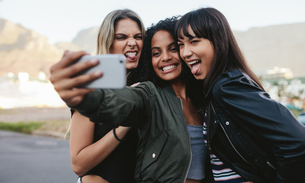 Smiling girls making selfie with smart phone