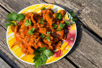 Chicken gizzard stew in plate on rustic wooden table
