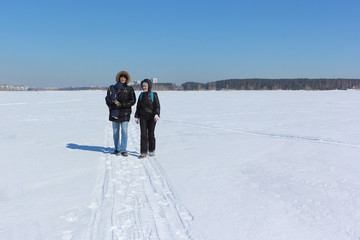 Fototapeta na wymiar Man, woman and the child walking on the snow river in the winter, Siberia, Russia