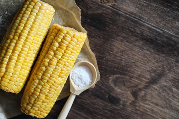 Boiled corn cob with salt on a wood