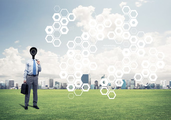 Camera headed man standing on green grass against modern citysca