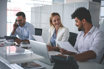 Business people working in office. Business people having coffee break. African man holding document and using laptop.