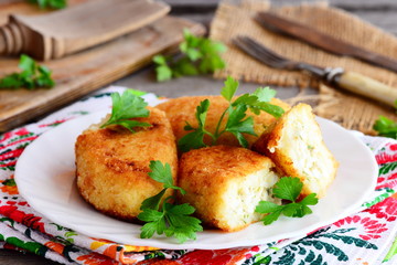 Spicy cauliflower potato patties with egg filling on a white plate. Fried patties cooked with mixed boiled vegetables and eggs. Easy home vegetarian recipe. Rustic style. Closeup
