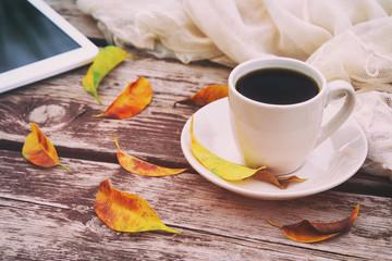 Digital tablet and cup of coffee on old wooden table outdoor in the park