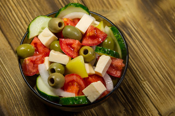 Greek salad in glass bowl on wooden table