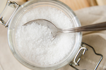 Fototapeta na wymiar White sea salt white napkin in a jar on an iron spoon