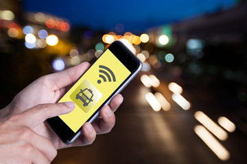 Hand of man using smartphone call taxi by application smartphone and wifi networking with bokeh background of car on the road.