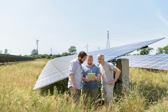 Local Community Members Using Digital Tablet App To Look At Energy Performance Of Solar Farm