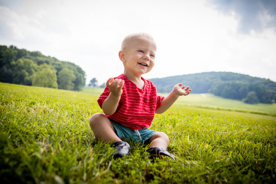 Happy baby boy sitting in rural field