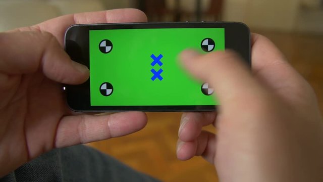 Smart Phone held by hands. Green screen Chroma Key. Close up. Tracking motion. Horizontal. Person sitting, telephone on the leg, blue jeans / pants. - . Swipe left / right animation.