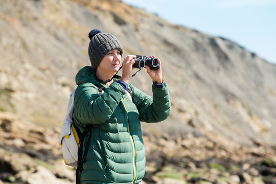  Woman using binoculars on rock, Folkestone, UK
