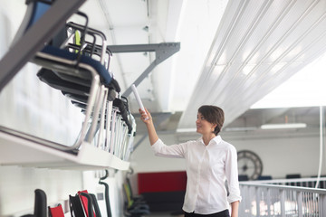 Young female sales manager pointing at chairs in office furniture store