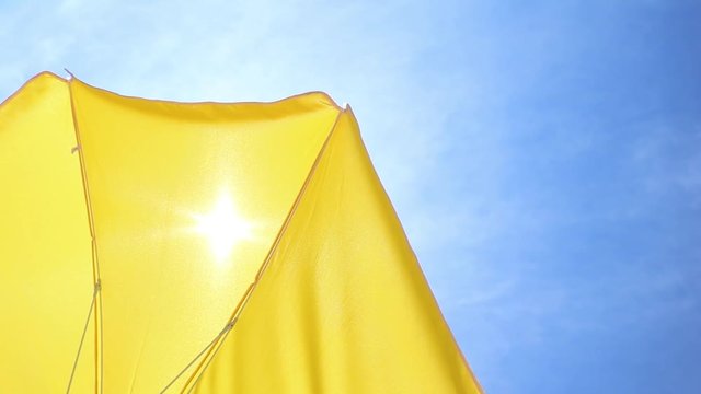 Part of a yellow parasol against the blue summer sky