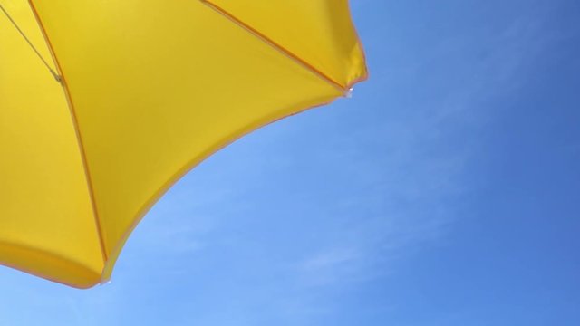 Part of a yellow parasol against the blue summer sky