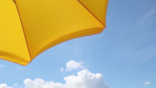 Part of a yellow parasol against the blue summer sky