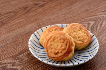 Chinese moon cake -- food for Chinese mid-autumn festival on a colorful plate isolated on wooden background