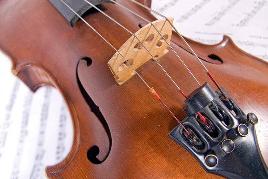 Close up of a violin lying on printed sheet music.