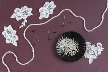Pins, white laces and beads on a saucer