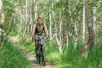 Naklejka premium a young man rides through a forest path on a bike