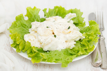 potato salad on white plate on wooden background
