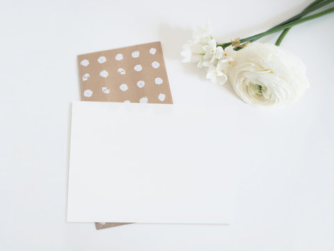 Styled stock photo. Feminine digital product mockup with buttercup and daffodil flowers, and blank list of paper . White background. Flat lay, top view.