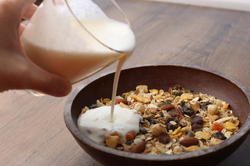 Muesli with nuts and tropical dried fruits. Healthy breakfast: flakes cereal in wooden plate.
