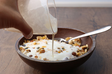 Muesli with nuts and tropical dried fruits. Healthy breakfast: flakes cereal in wooden plate.