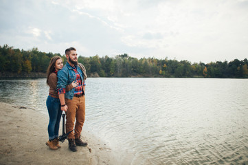 A loving couple stand on the bank of a mountain river, embracing each other