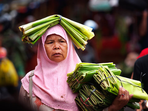 Sumatran Muslim Woman: Wearing Hijab and Carrying Banana Leaves on Her Head, Selling in the Crowd at an Asian Market