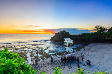 Tourist gathering taking a group photo at Batu Bolong Beach,Bali,Indonesia,with sunset background.