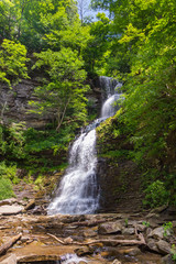 Cathedral Falls in southern West Virginia, a tall beautiful waterfall and stream coming from a rocky outcrop through the sunlit trees of summertime.