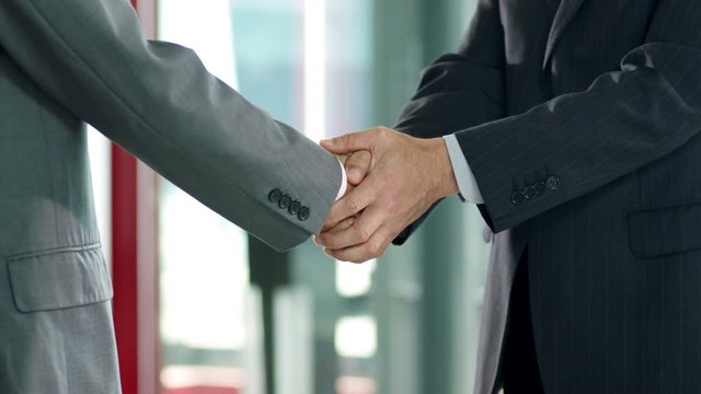 asian corporate executive welcoming and shaking hands with client in company lobby