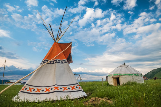 Teepee and yurt set on the green meadow with blue sky on the background