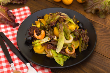 Fresh mix salad with shrimps, yellow cherry tomatoes and balsamic sauce. on wooden background. Close-up. Top view