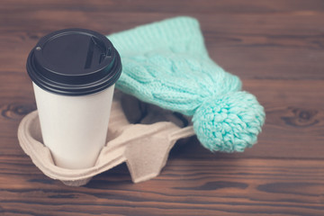 Knitwear mint hat and cup of coffee takeaway on wooden background