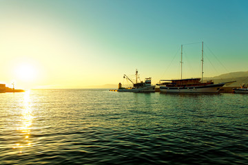 Naklejka premium Fishing trawler and a sailboat moored in the harbor of a small town Postira - Croatia, island Brac