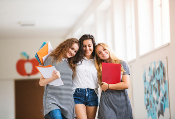 Three teenage girls in high school hall during break.