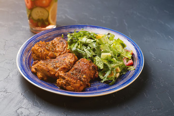 Platter of chicken thighs piri piri coated in hot sauce with salad.
