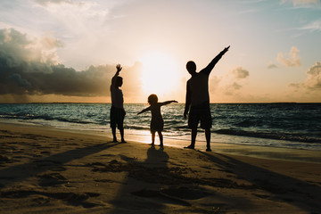 Fototapeta premium father with son and daughter silhouettes play at sunset beach