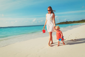 mother and cute little daughter walking on beach